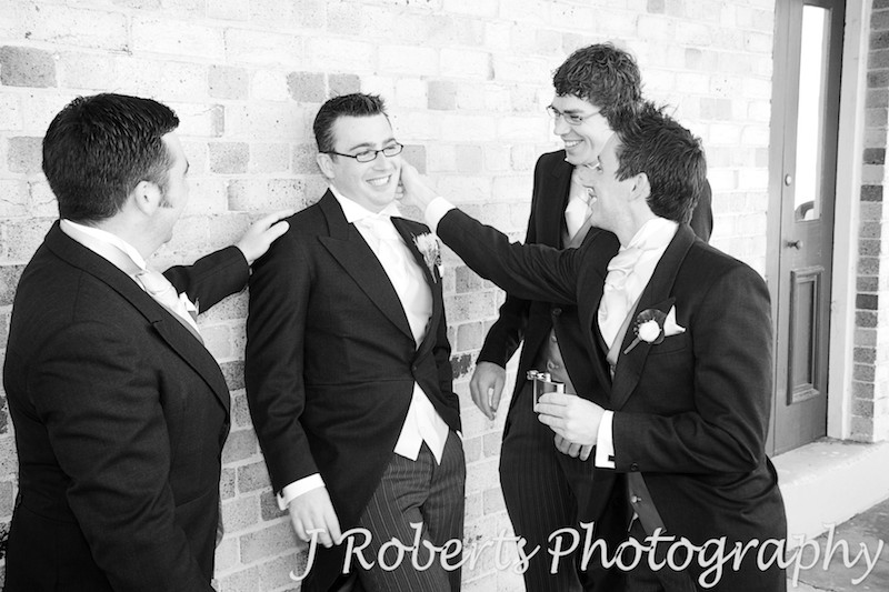 B&W groomsmen playing around prior to wedding, Georges Head Sydney - wedding photography sydney